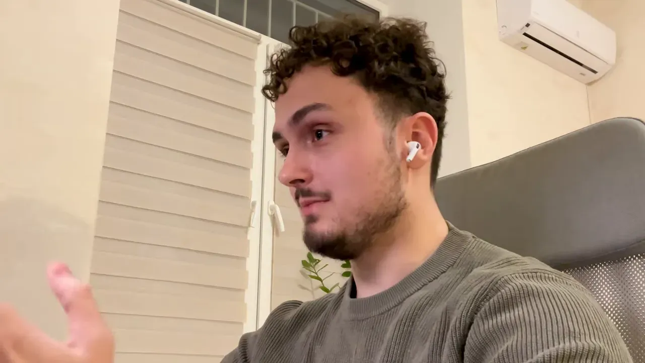 Founder speaking during an interview in a home office, wearing earbuds and gesturing